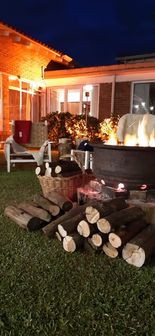 An outdoor fire pit with logs, a wicker basket, and a chair.