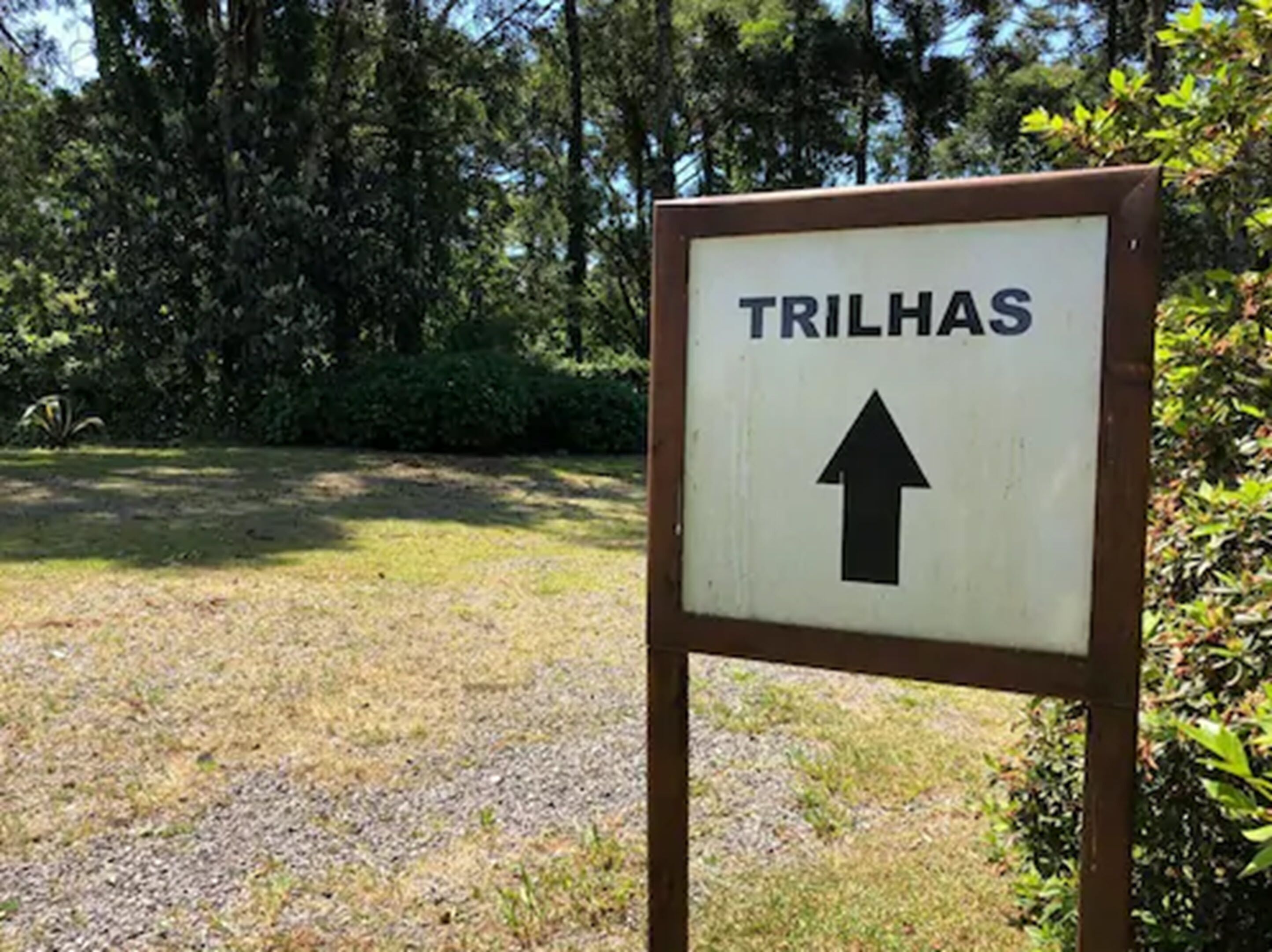 A sign with the word "TRILHAS" and an upward arrow, indicating a direction.