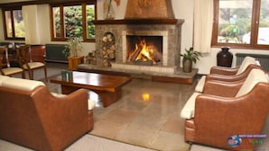 Amplia sala de estar con chimenea de piedra, sofás de cuero y una mesa de centro.