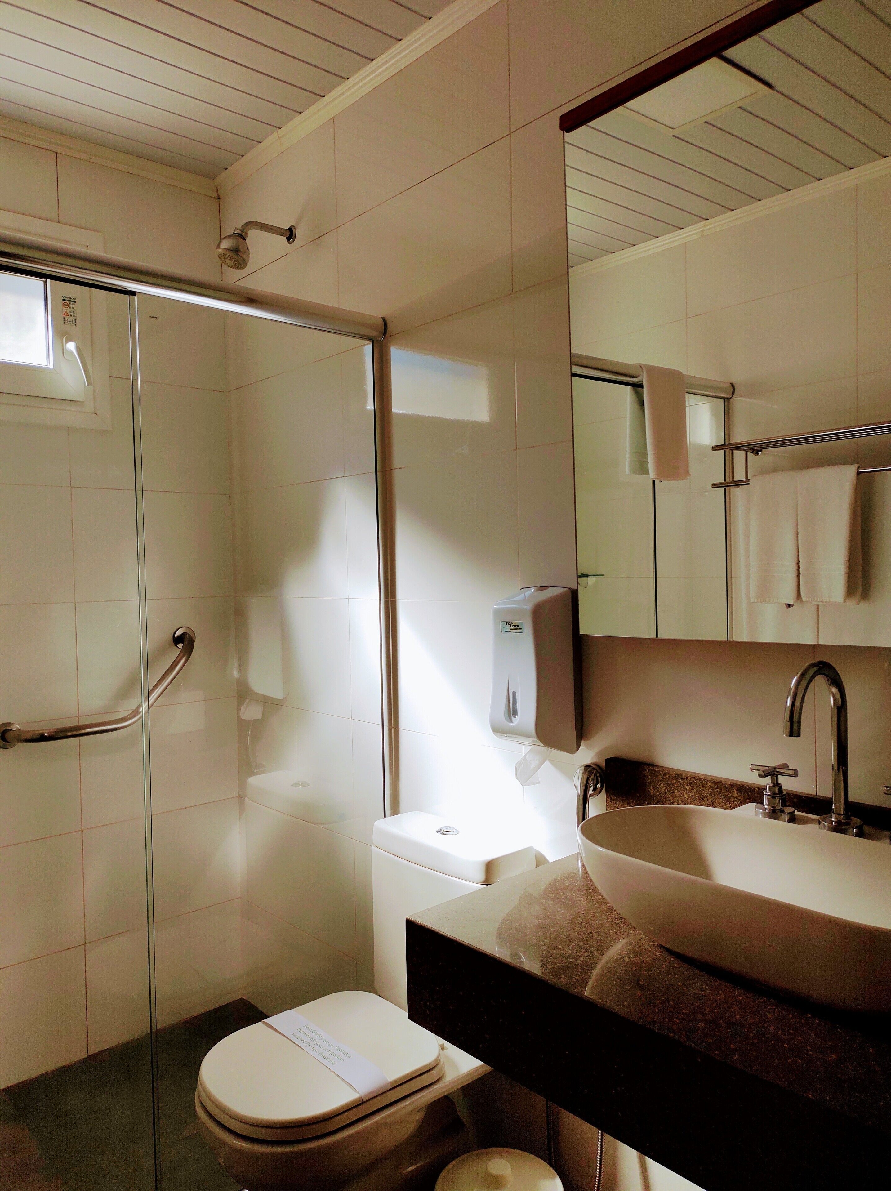 Et badeværelse med brusebad, toilet, håndvask og hårtørrer.
