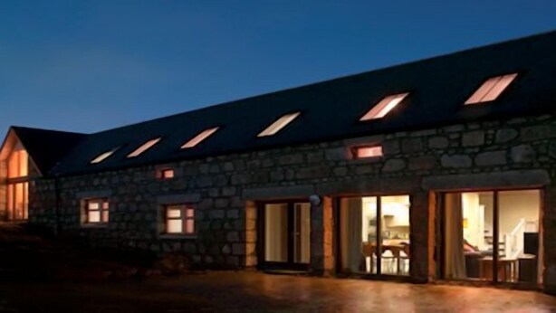A stone building with multiple windows and a sloped roof, likely a hotel or guesthouse.
