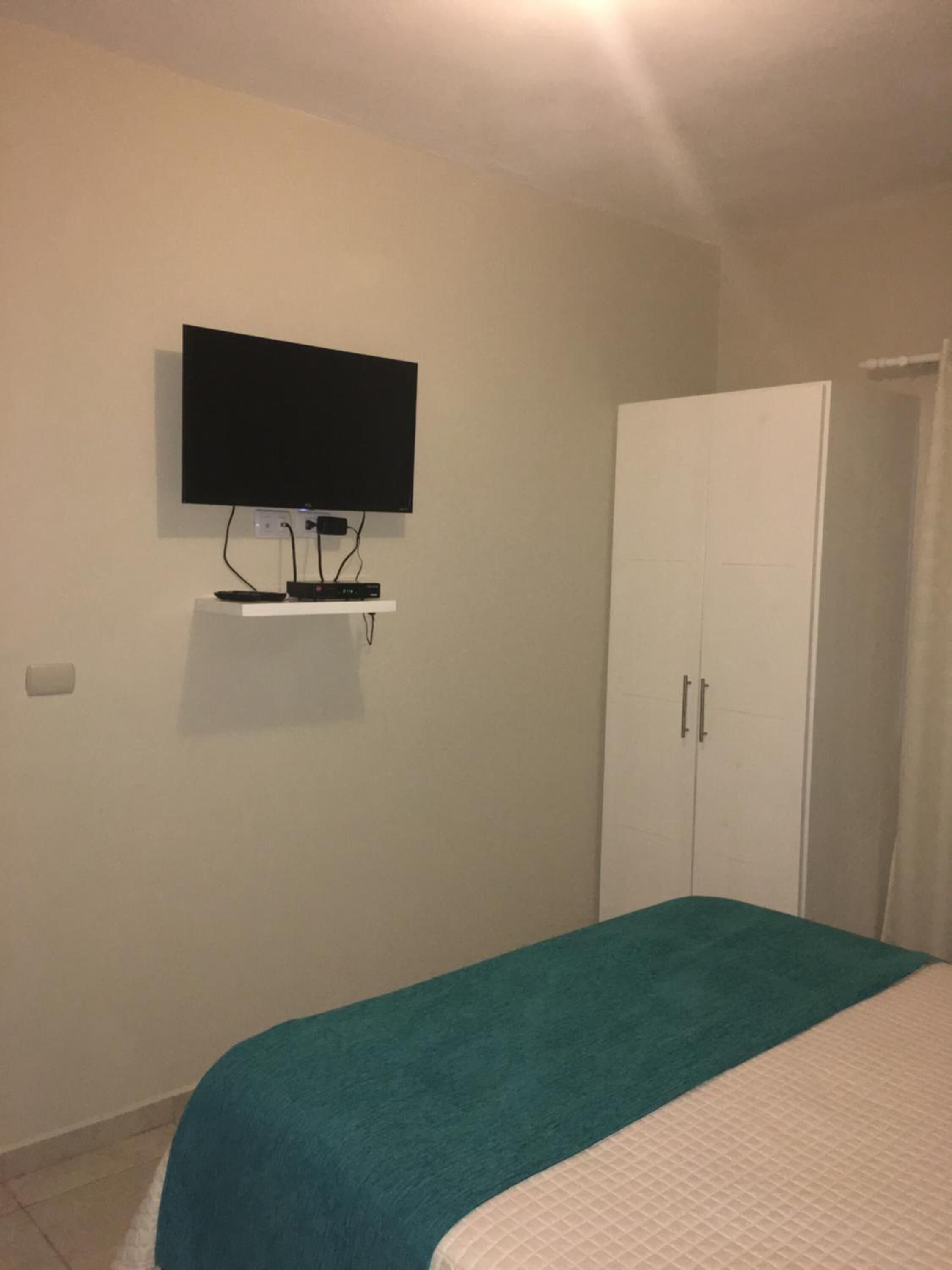 Una camera da letto con un letto, una televisione a parete e un armadio.