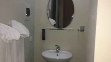 Un baño pequeño con un lavamanos pedestal, un espejo encima y una toalla colgada en la pared.