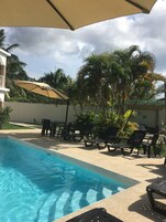 Una piscina al aire libre, sombrillas, sillones reclinables de piscina