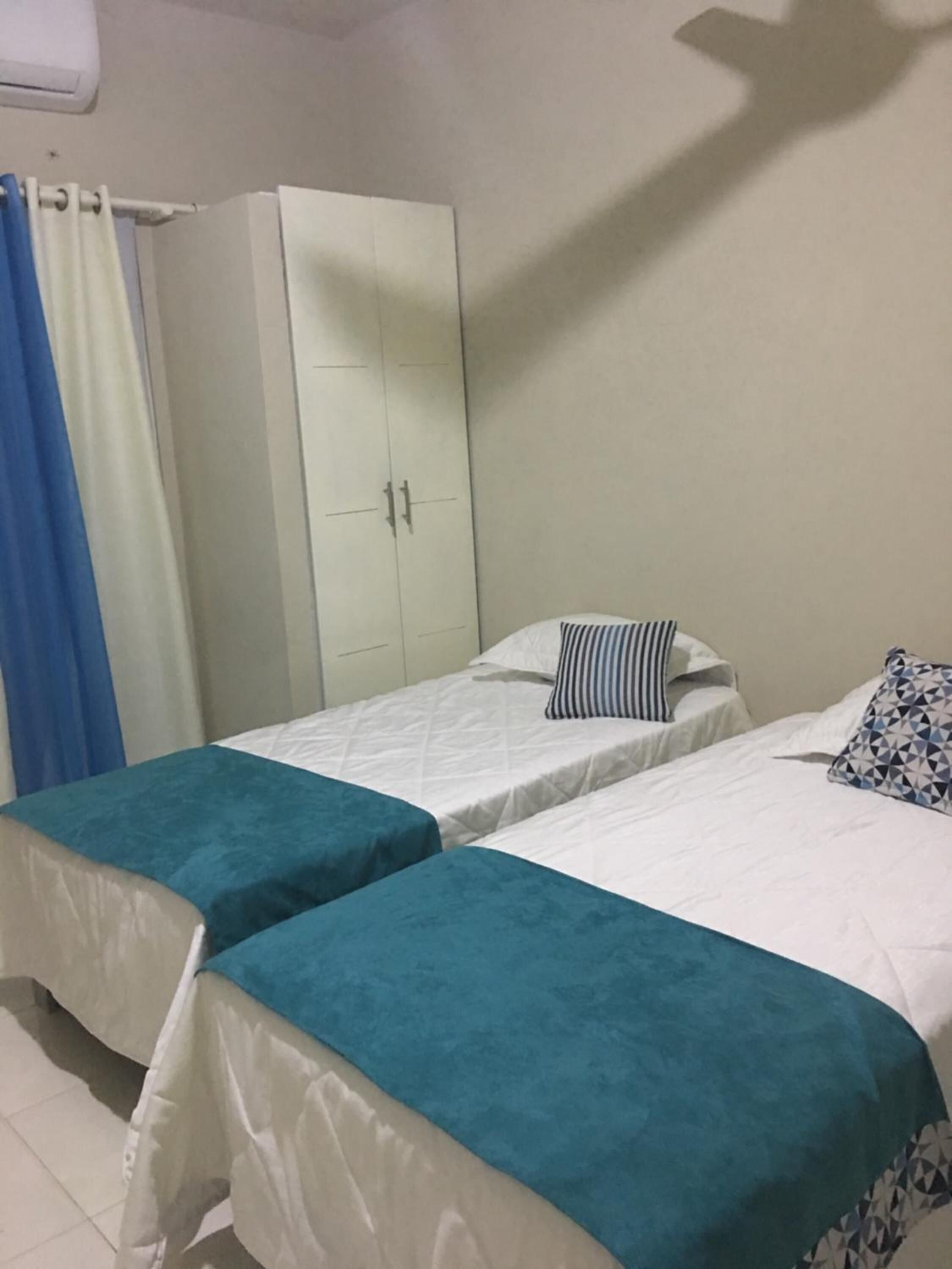 A room with two single beds, a wardrobe, and a curtain.