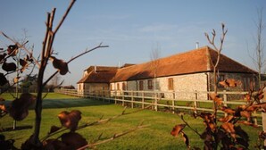 A rustic stone building with a thatched roof, surrounded by a wooden fence and a grassy area. - The Run, West Lavant 173744 (Chichester)