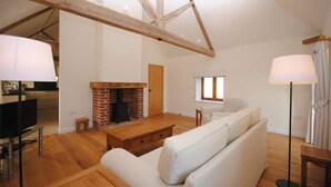 A spacious living room with a fireplace, wooden beams, a sofa, and a television. - The Run, West Lavant 173744 (Chichester)