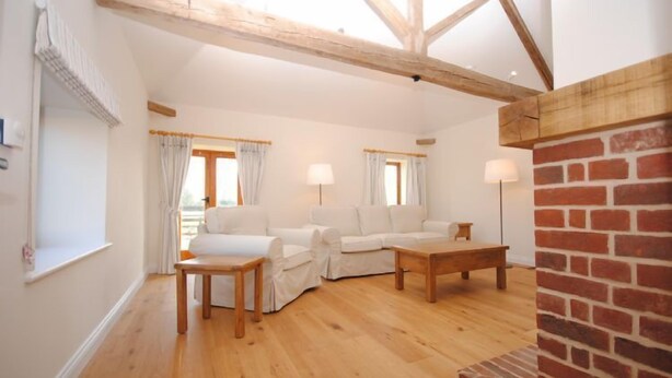 A spacious living room with a wooden floor, a brick fireplace, and a white sofa set. - The Run, West Lavant 173744 (Chichester)