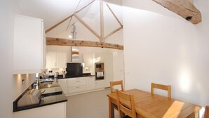 A compact kitchen with white cabinets, a black countertop, and wooden beams on the ceiling. - The Run, West Lavant 173744 (Chichester)