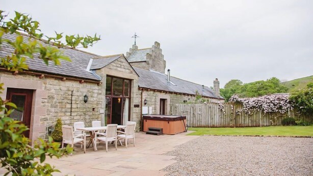 A stone building with a patio area featuring outdoor seating and a hot tub. - Watson Cottage (Hot Tub) (Brampton)
