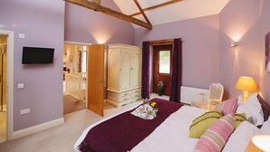 A bedroom with a large bed, a wardrobe, a television, and a window with curtains. - Watson Cottage (Hot Tub) (Brampton)