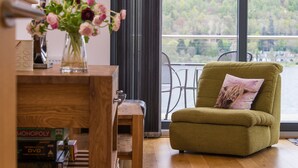A modern living room with a green armchair, a wooden coffee table, and a vase of flowers.