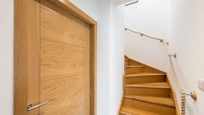 A wooden door with a handle and a wooden staircase with a rope handrail.