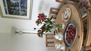 A dining table with a vase of flowers, white teacups, saucers, and a decorative plate. - Edmondston House 163451 (Kelso)