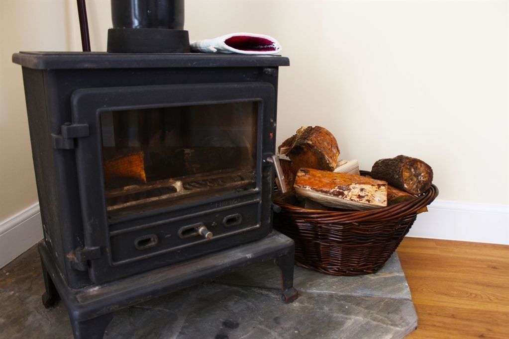 A wood-burning stove with a basket of bread next to it.