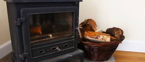 A wood-burning stove with a basket of bread next to it.
