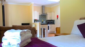 Ett hotellrum med en säng, ett litet pentry och utsikt över vardagsrummet.