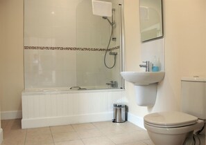 A modern bathroom with a glass-enclosed shower, a white bathtub, a sink, and a toilet. - Chestnut Garden Cottage (Alexandria)