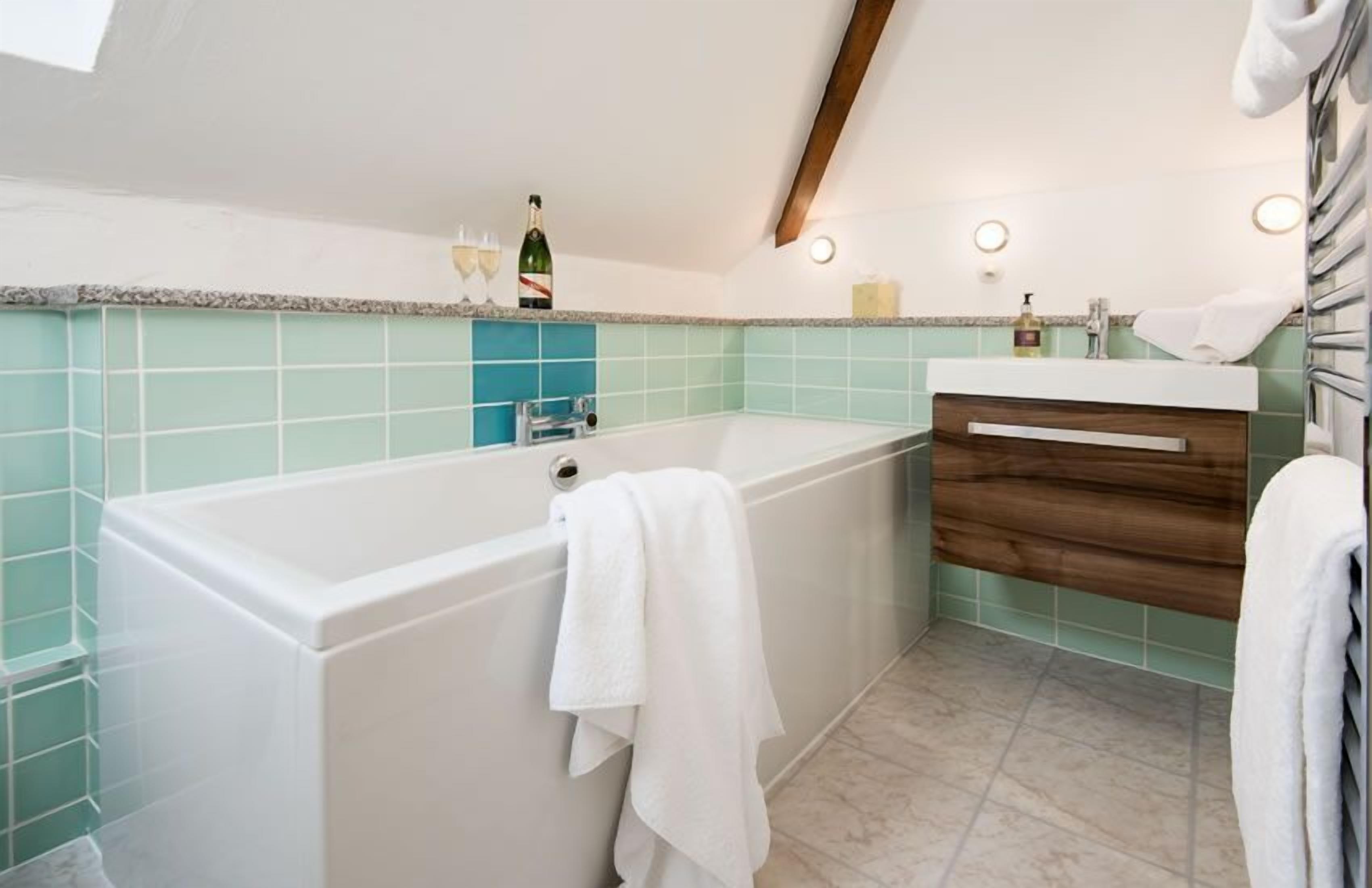 Un baño con bañera, tocador de madera y salpicadero de azulejos.