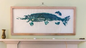 A framed artwork of a fish on a wall above a fireplace. - Turnigil (Isle of Colonsay)