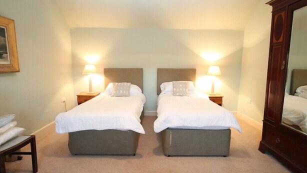 A double room with two beds, each with a nightstand and a lamp. - Scalasaig Farmhouse (Isle of Colonsay)