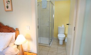 Quarto com cama, luminária de cabeceira e quadro na parede.
