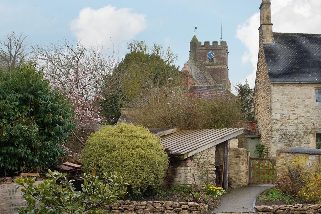 Un bâtiment en pierre avec un petit jardin et un chemin menant à une porte.
