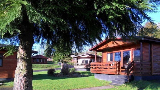 Een houten lodge met een veranda en een verzorgd gazon.