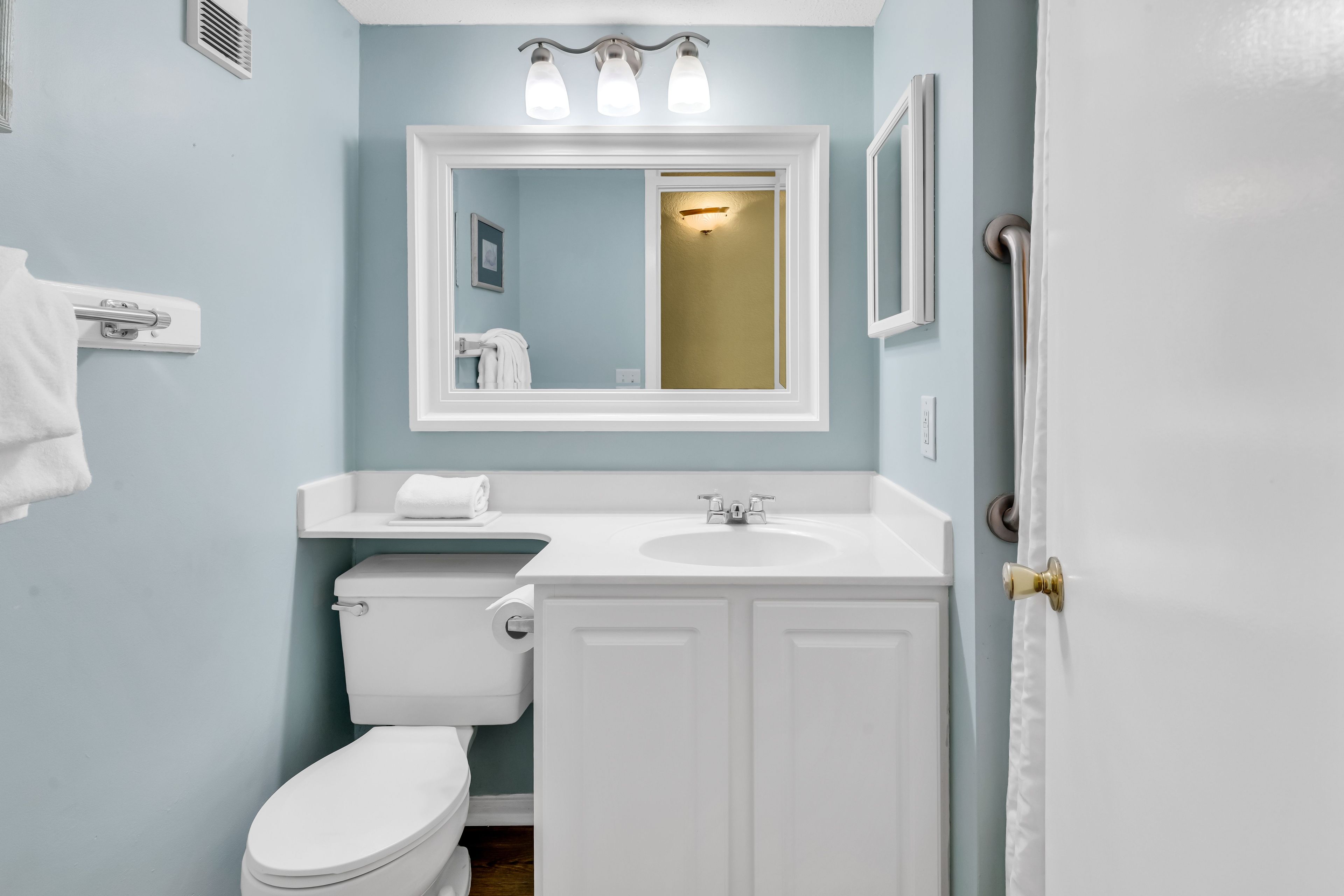 A bathroom with a toilet, sink, and mirror.