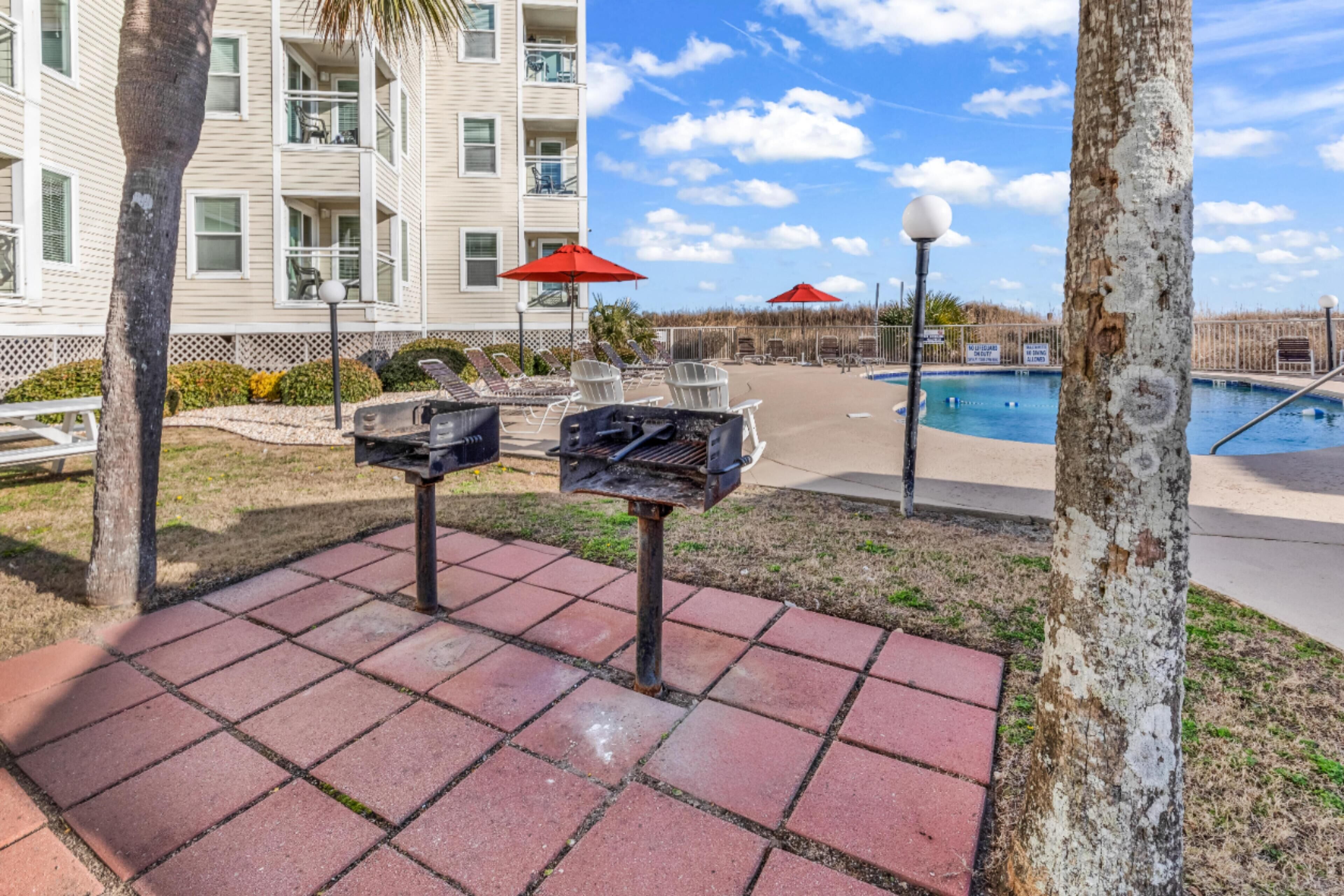 Un espace aménagé au bord de la piscine, avec des chaises longues, un barbecue et une piscine.