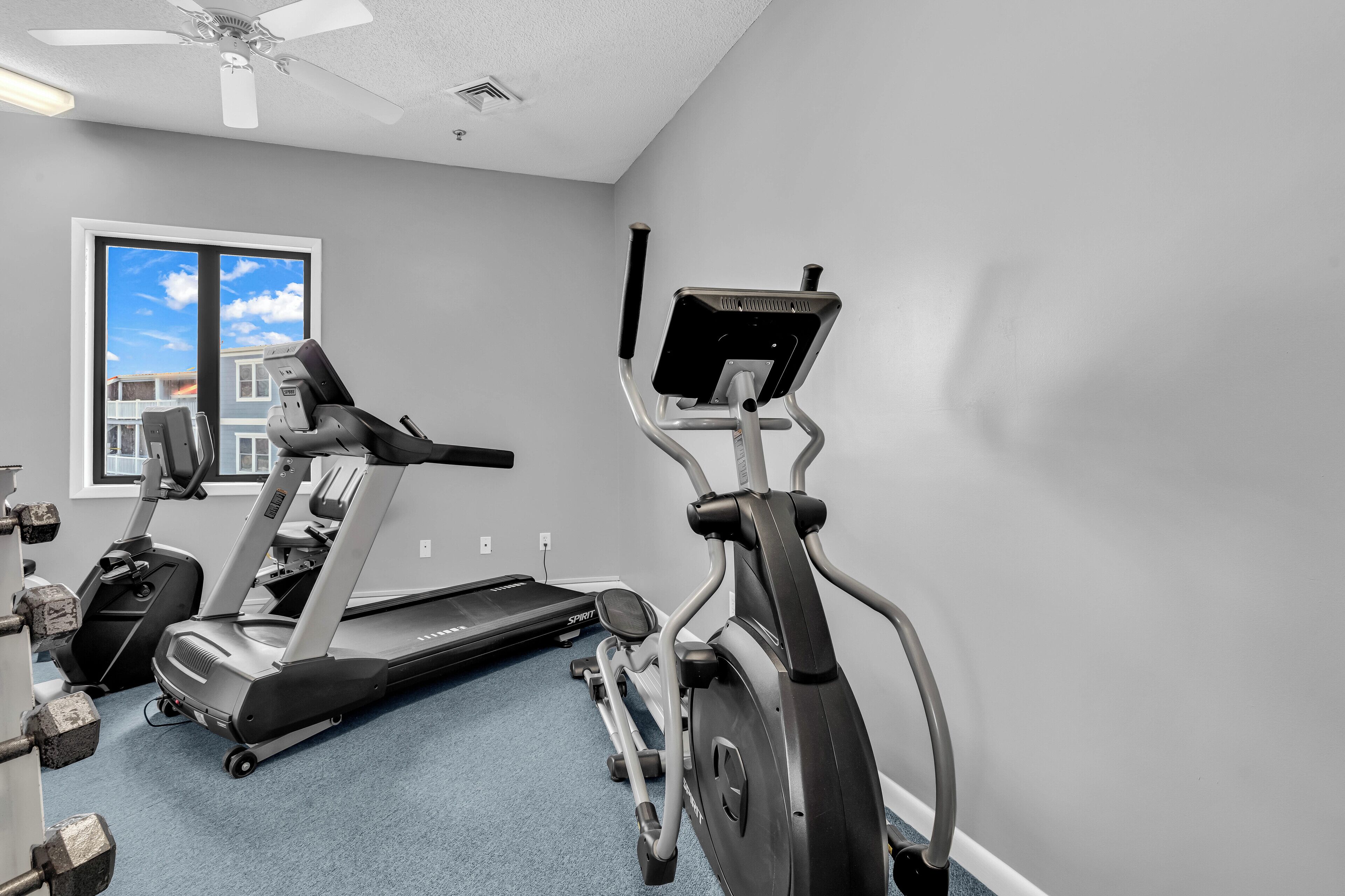 Une salle de sport équipée de tapis de course, de vélos elliptiques et d’haltères.