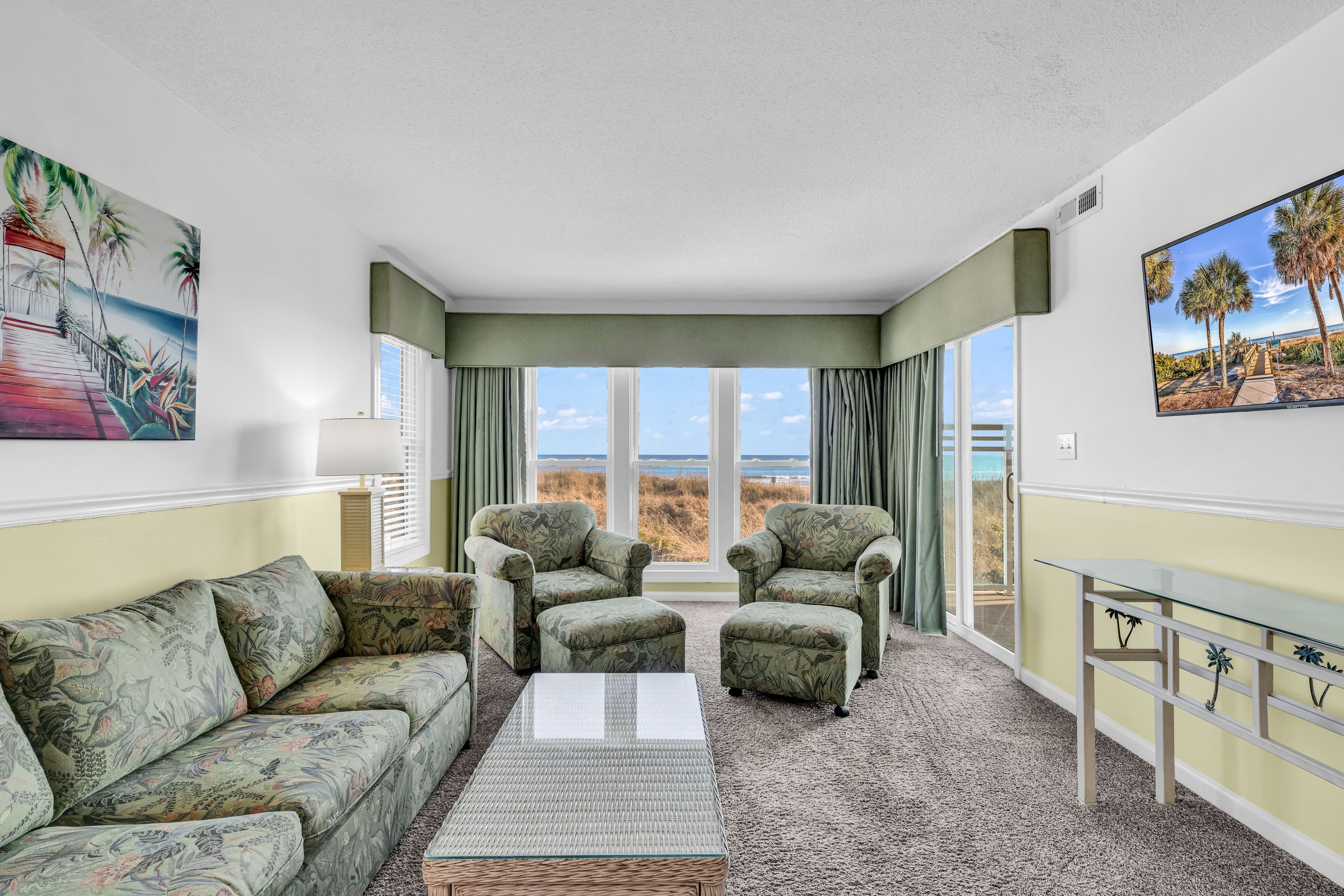 A room with a large window, two armchairs, a sofa, and a coffee table.