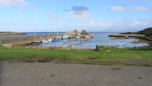 A coastal harbor with boats docked, a pier, and a rocky shoreline. - Harbour (Isle of Colonsay)