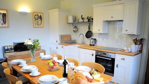 Une cuisine avec des meubles blancs, un plan de travail en bois et une table à manger dressée pour le repas.