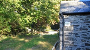 A stone cottage named 'Pondside Cottage' with a metal gate and a stone wall.