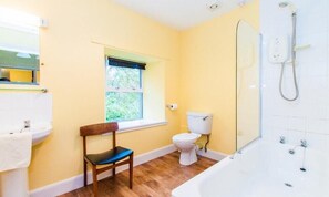 A bathroom with a bathtub, toilet, and a window.