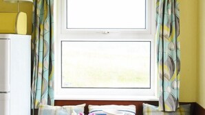 A room with a window, curtains, a bed, and a lamp.