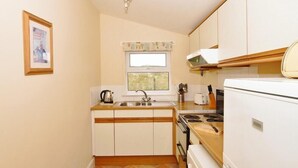 A compact kitchen with a sink, stove, and white cabinets.