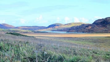 A natural landscape with rolling hills, a body of water, and a fenced area.