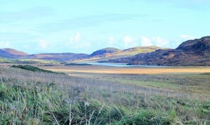 A natural landscape with rolling hills, a body of water, and a fenced area.