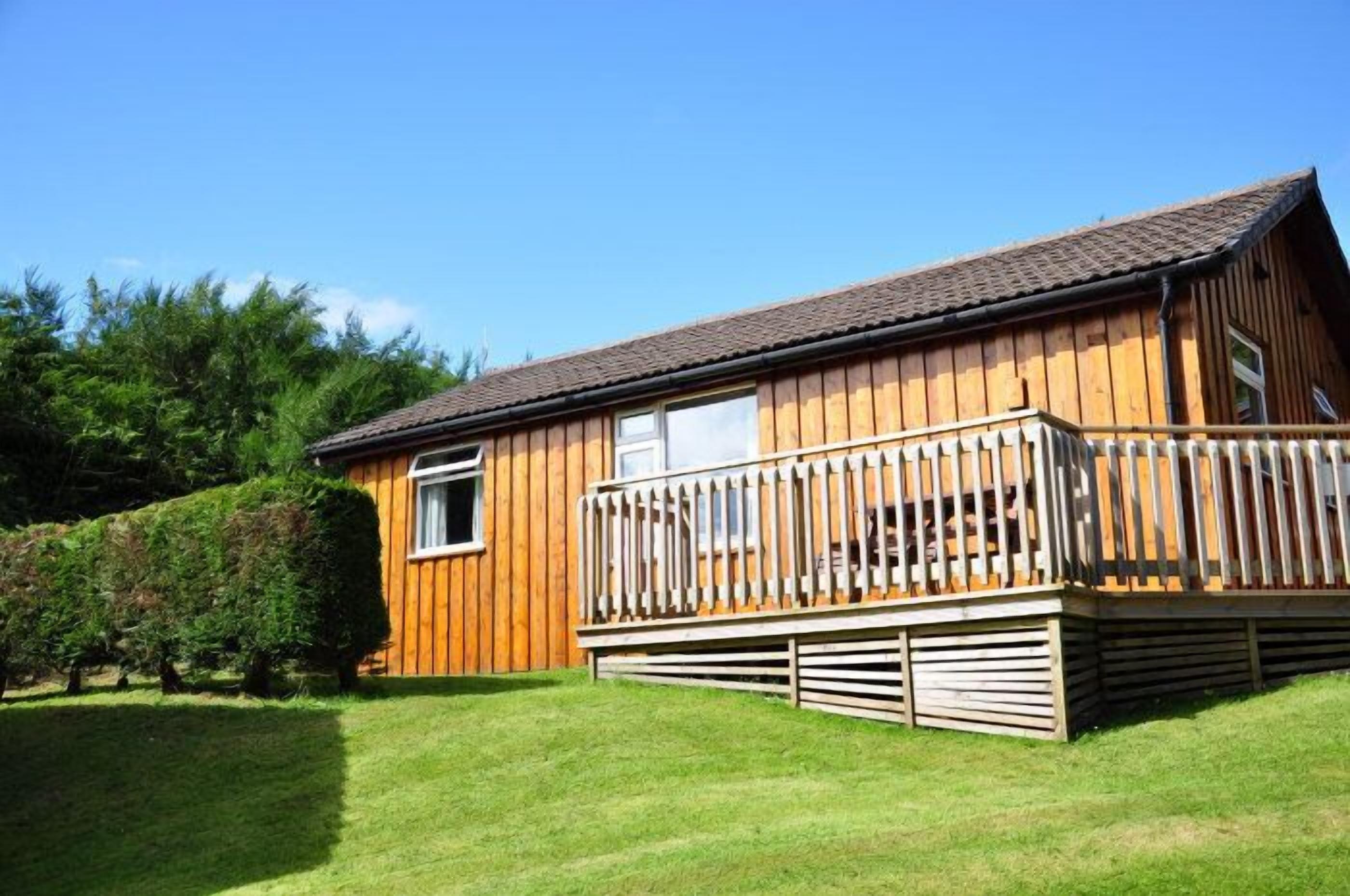 A wooden cabin with a balcony, a window, and a door.