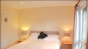 Ein Hotelzimmer mit einem großen Bett, zwei Nachttischlampen, einem Nachttisch und einem Fenster mit Vorhängen.
