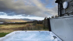 A hot tub with a view of a lake and mountains. - Mountain View Lodge 375948 (Kingussie)