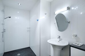 A modern bathroom with a glass shower enclosure, a white sink with a mirror, and a black countertop. - Mountain View Lodge 375948 (Kingussie)