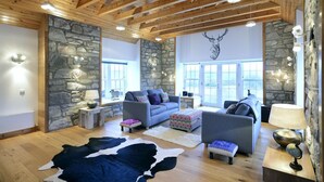A cozy living room with stone walls, wooden beams, and a cowhide rug. - Mountain View Lodge 375948 (Kingussie)