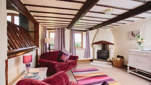 A cozy living room with a fireplace, red velvet sofas, and a wooden ceiling. - Low Barn (Brampton)