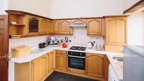 A kitchen with wooden cabinets, a microwave, a stove, and a sink. - Low Barn (Brampton)