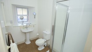 A bathroom with a pedestal sink, a toilet, a shower with a glass door, and a window above the sink. - Allt Bronach (Newtonmore)