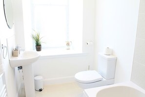 A small, bright bathroom with a sink, toilet, and bathtub.
