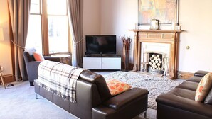 A living room with a fireplace, a television, and two sofas. - 10 Murray Park  375840 (St. Andrews)